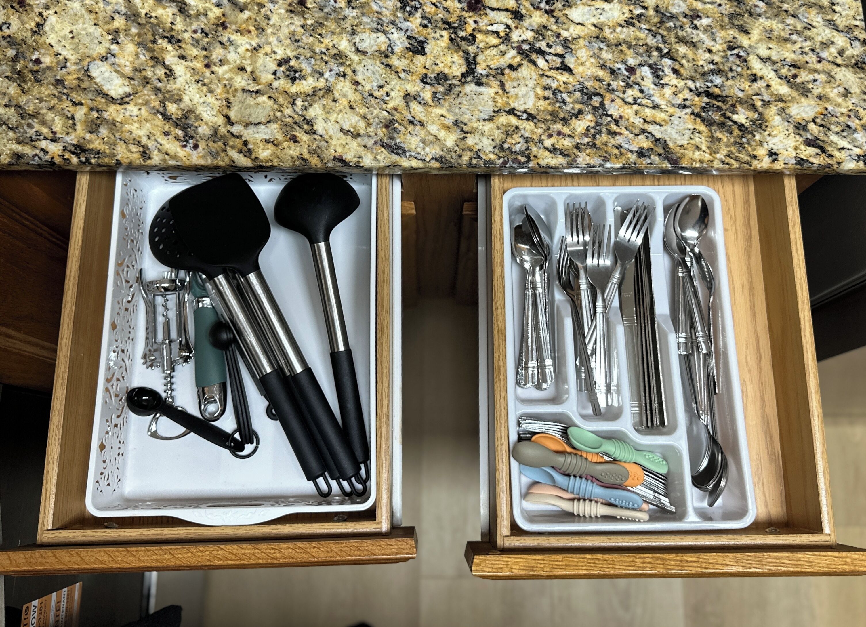 Un cajón con un juego de utensilios de cocina, incluyendo una espátula, una cuchara grande y unas pinzas.