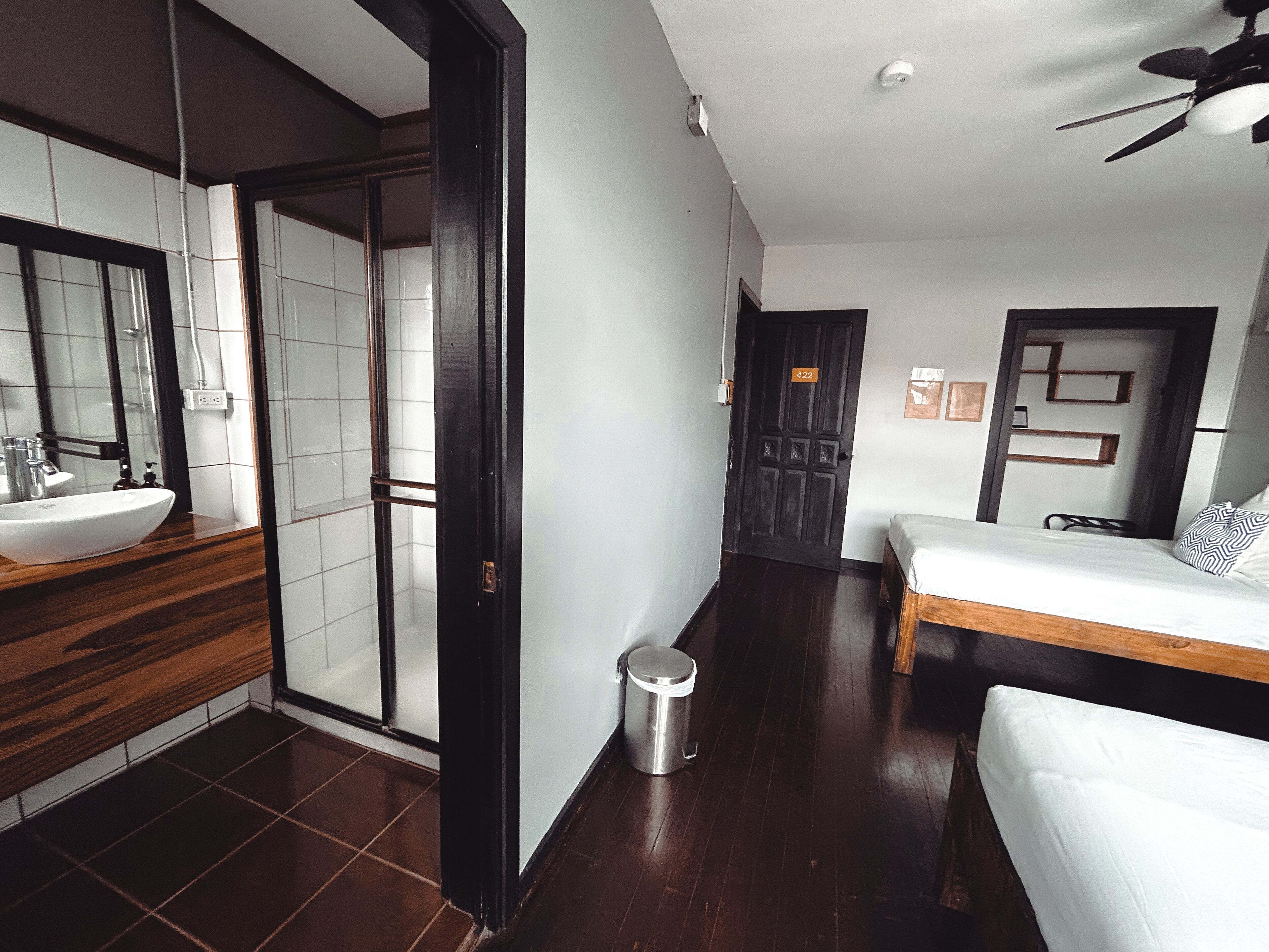 A modern bathroom with a large sink, mirror, and dark wooden floor.