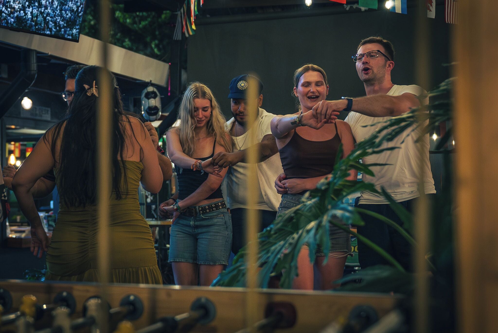 A group of people in a social setting with a reflective surface in the foreground.