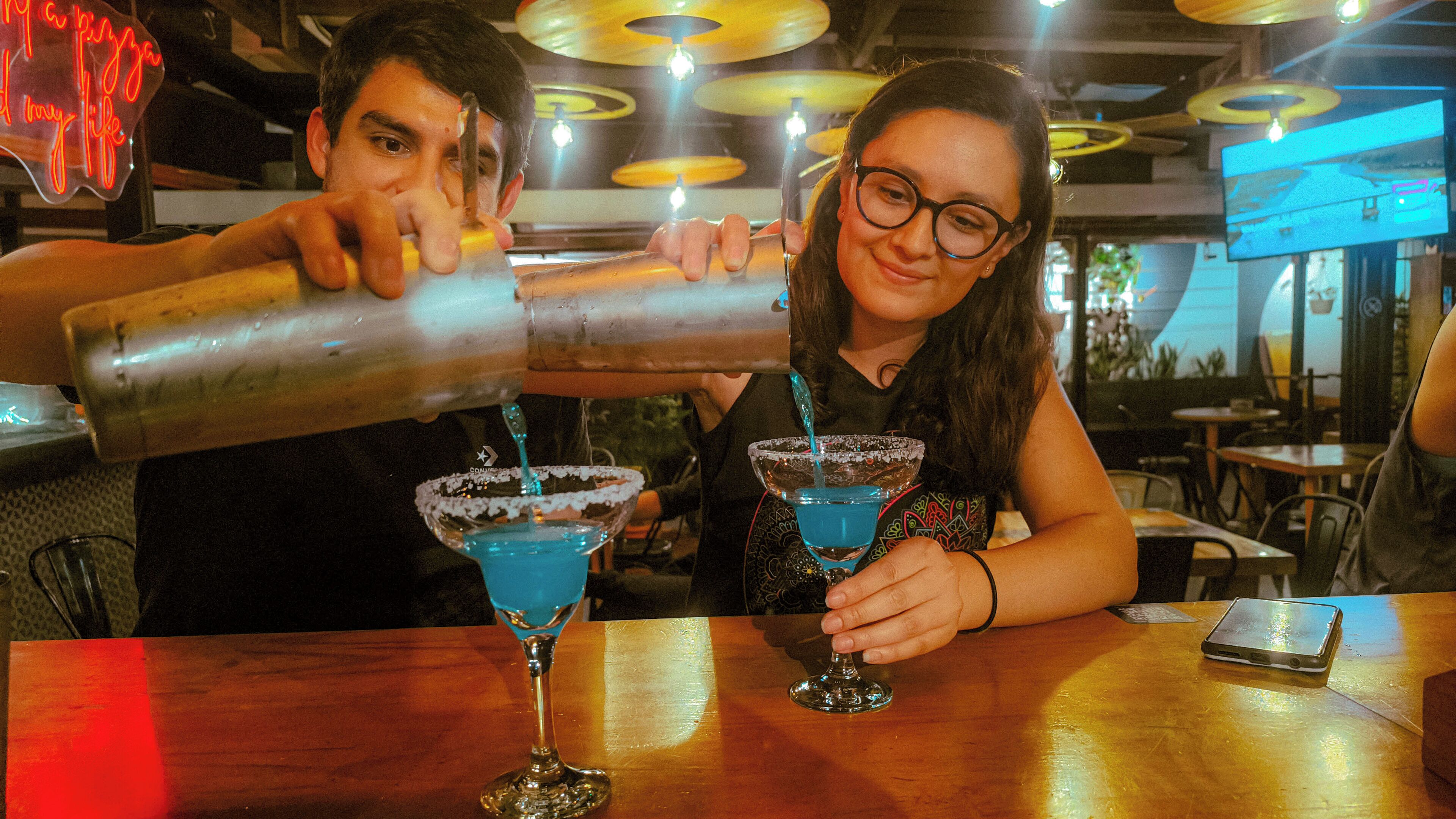 A bar setting with two people preparing drinks.