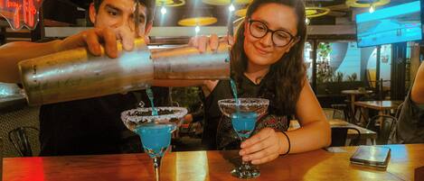 A bar setting with two people preparing drinks.