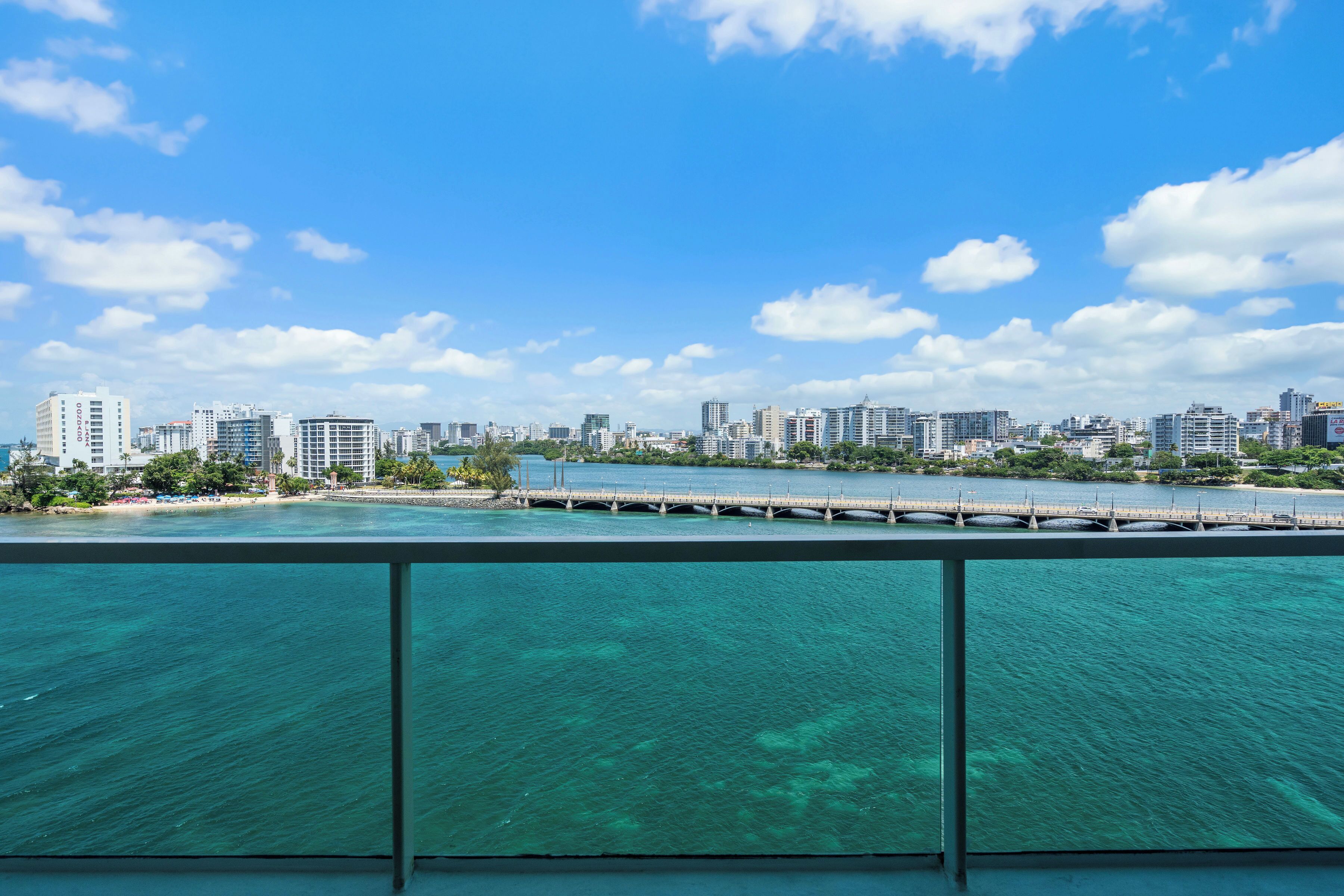 A city skyline with a bridge over water, buildings, and a clear sky.
