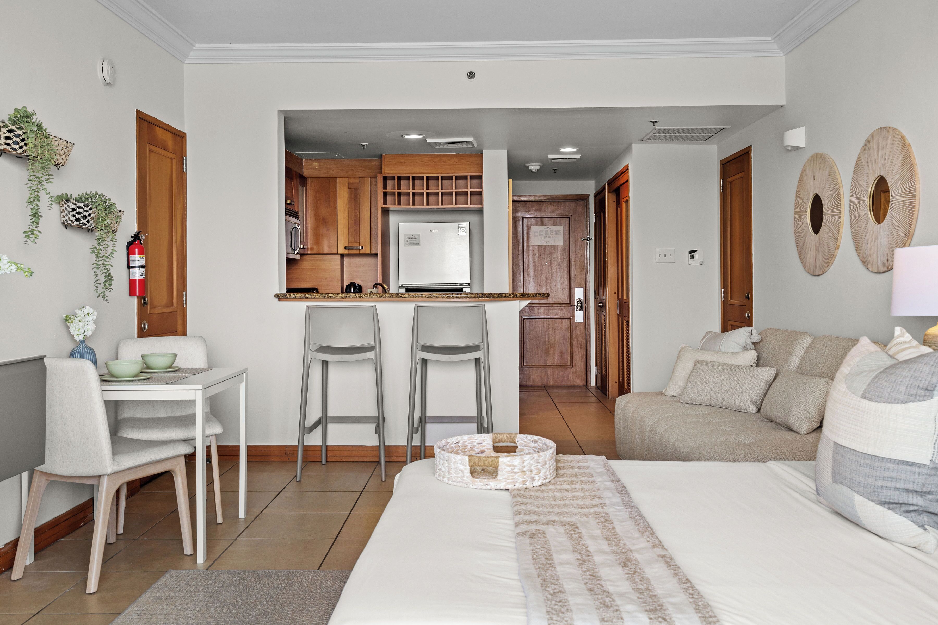 Una habitación de hotel moderna con una cama grande, un comedor con mesa y sillas, una kitchenette y una sala de estar con sofá.