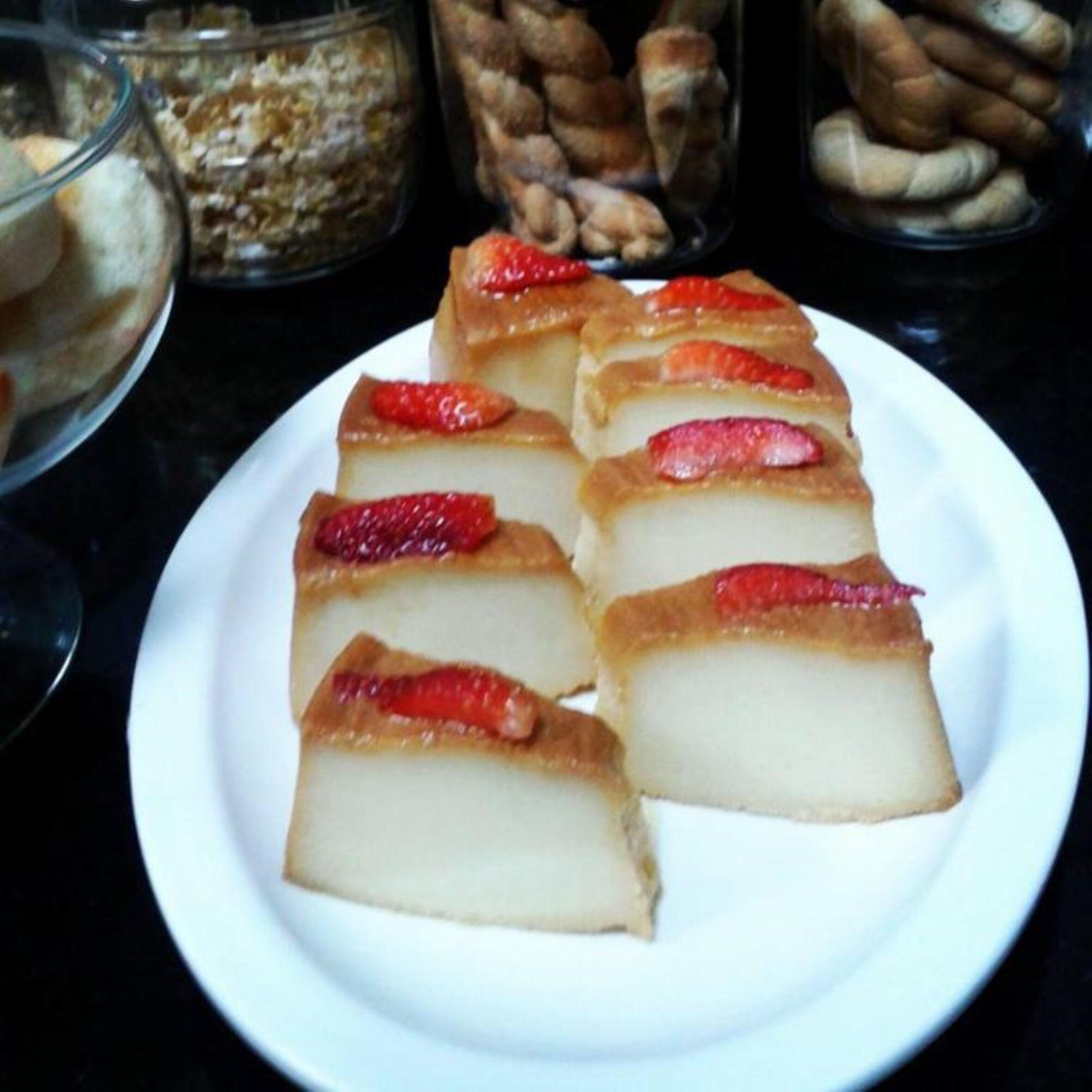 A plate of layered dessert cubes with strawberries on top.