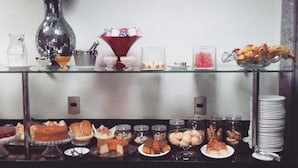 Una mesa de buffet con diferentes opciones de comida, un jarrón con flores y un cuenco de vidrio decorativo.