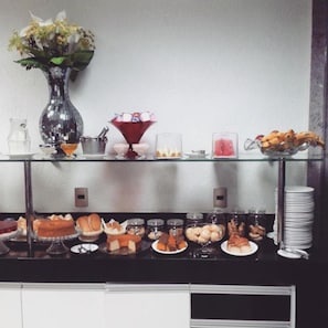 A buffet setup with various food items, a vase with flowers, and a decorative glass bowl.