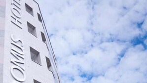 Un edificio de hotel con diseño moderno, que presenta una serie de ventanas rectangulares y un llamativo letrero con la palabra 'HOTELS' en la fachada.