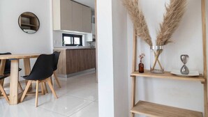 A modern kitchen with wooden cabinets, a dining area with a wooden table and chairs, and a shelf with decorative items. - 2 rooms Las Lomitas (Lomas de Zamora)