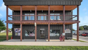 Een gebouw met twee verdiepingen, een houten balkon, een bordje voor een winkel in op maat gemaakte houten borden en een muurschildering aan de zijkant.