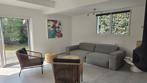 A modern living room with a sectional sofa, two wicker chairs, a coffee table, and a fireplace. - Luxury house near town and 150m from the ocean (Saint-Gildas-de-Rhuys)