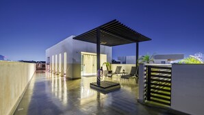 Un edificio moderno con un patio coperto, un'area salotto e una vista sullo skyline cittadino.