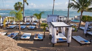 A beachside resort with multiple sunbeds and a hot tub.