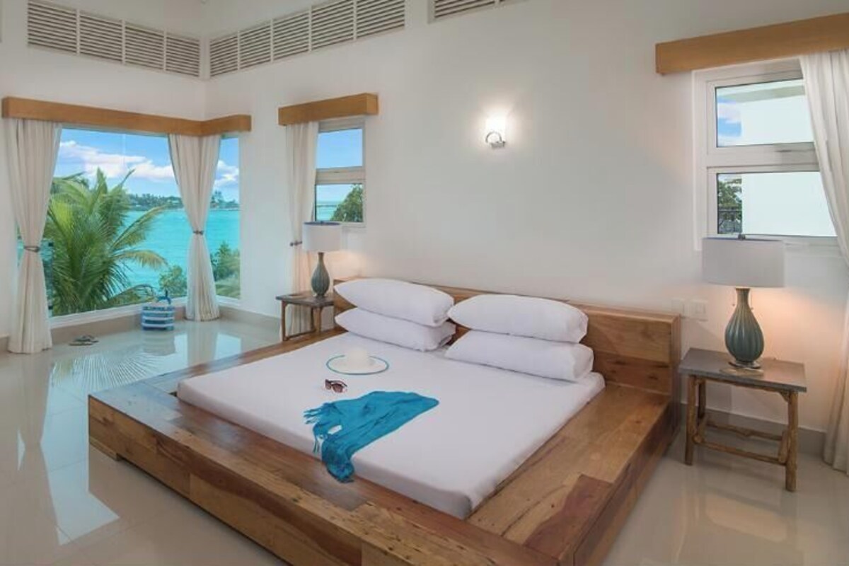 A spacious bedroom with a large bed, a view of the ocean, and a balcony.