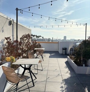 Un patio al aire libre con mesa y sillas, luces colgantes y plantas.