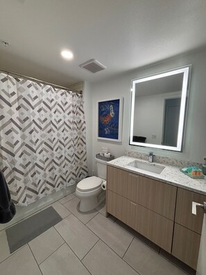 Un baño con cortina de ducha, inodoro, lavabo y armario.