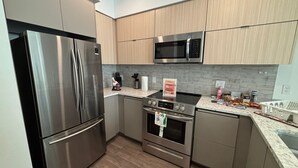 A modern kitchen with stainless steel appliances, wooden cabinets, and a granite countertop.