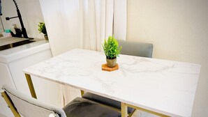 Une petite cuisine moderne avec un plan de travail en marbre, une seule chaise et une plante en pot.