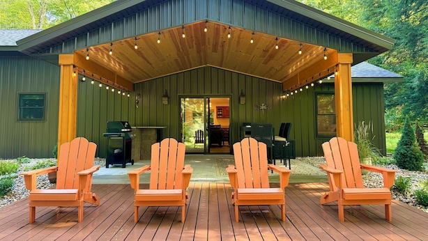 Een overdekt terras met houten stoelen en een barbecue.