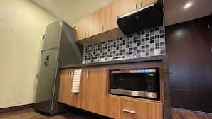 Een keuken met houten kastjes, een roestvrijstalen koelkast, een magnetron en een betegelde spatwand.