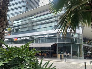 Un immeuble moderne abritant un café Starbucks et un restaurant Nacion Sushi au rez-de-chaussée.