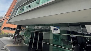 Een modern gebouw met een glazen gevel, een bord met 'LUGO Business Hotel' en een heldere lucht.