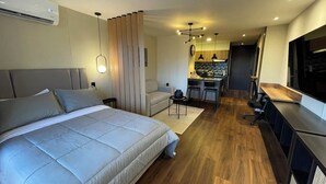 Een moderne hotelkamer met een groot bed, een bureau, een kitchenette en een televisie.