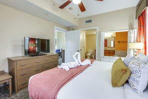 Une chambre d’hôtel avec un lit, une télévision, une commode et une salle de bain visible à travers une porte ouverte.