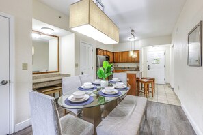 Un coin repas avec une table en verre dressée pour six personnes, entourée de chaises rembourrées.