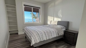 Ein Schlafzimmer mit einem Bett, einem Nachttisch, einem Fenster mit Blick und einer eingebauten Ablage.