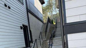 Eine schmale Außentreppe führt zu einem Gebäude mit weißer Fassade und schwarzer Dekoration.