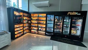 Un mercado Muda con estantes llenos de bocadillos y bebidas, y un refrigerador de Coca-Cola.