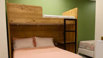 A bunk bed with a wooden headboard and a lower bed, both with white bedding. The room has green walls and a white floor.