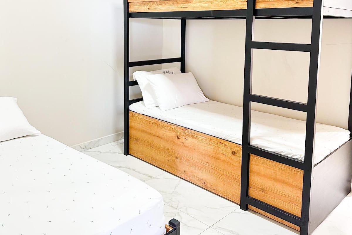 A bunk bed with a wooden headboard and black frame, a white mattress, and a pillow.
