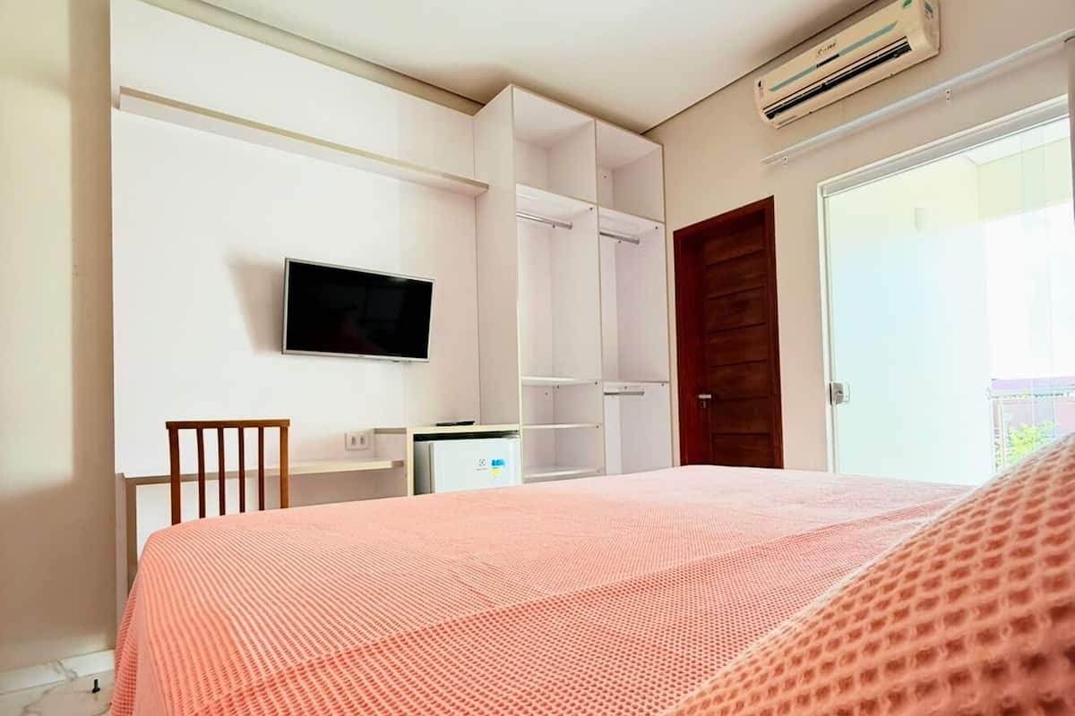 A bedroom with a bed, a TV, a desk, and a wardrobe.