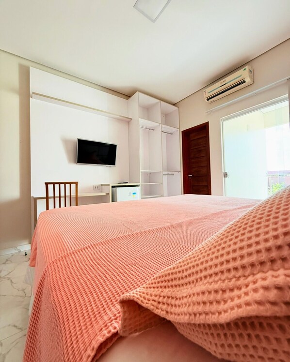 A bedroom with a bed, a TV, a desk, and a wardrobe. - Hotel Barruada (Boa Vista)