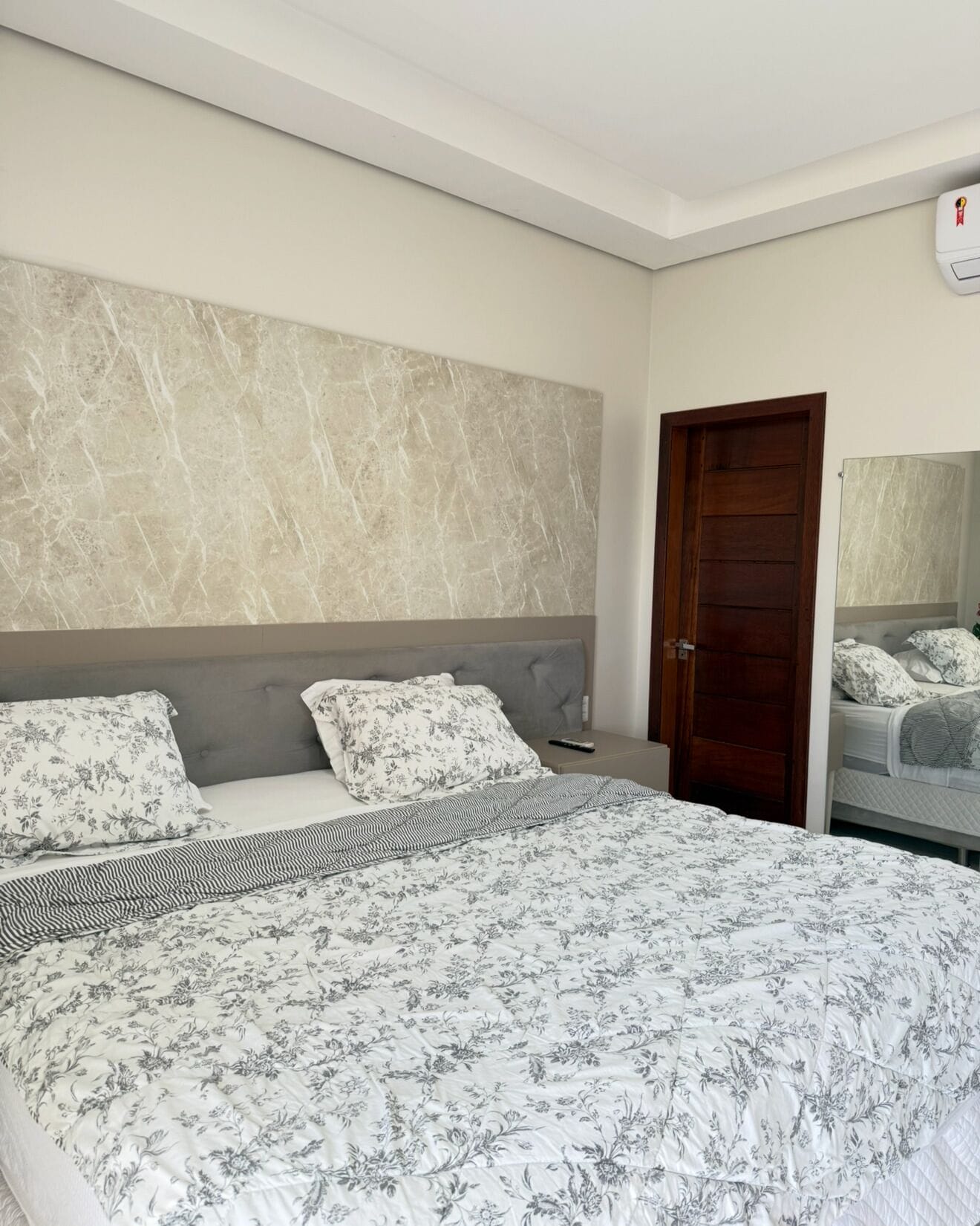 A bedroom with a large bed, a headboard, and a wooden door.