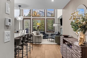 A modern kitchen with a dining area, large windows with mountain views, and a bar area.