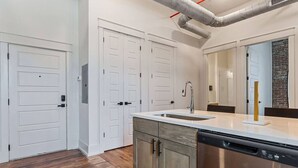 A modern kitchen with a dishwasher, a sink, and a double door closet.