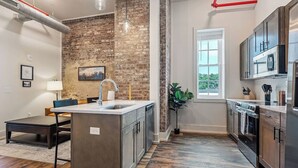 A modern kitchen with a brick accent wall, a central island with a sink, and stainless steel appliances.
