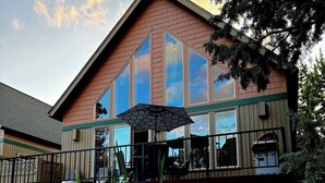 A building with large windows, a deck, and a view of a body of water. - Creekside Chalet with private hot tub (Redmond)
