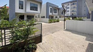 A modern residential complex with multiple apartment buildings, paved walkways, and some greenery.