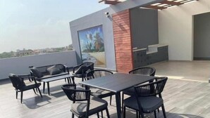 An outdoor patio with a table and chairs, a wooden wall, and a view of the city.