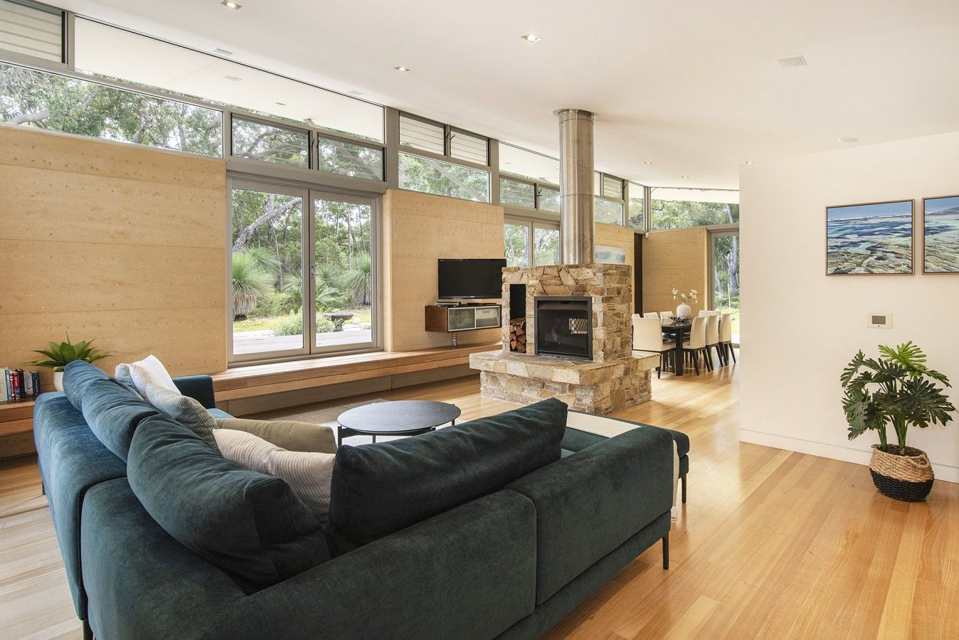 A modern living room with a stone fireplace, a large sofa, and a dining area with natural light.