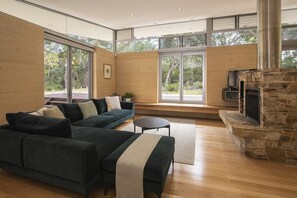 A modern living room with a sectional sofa, a fireplace, and large windows.
