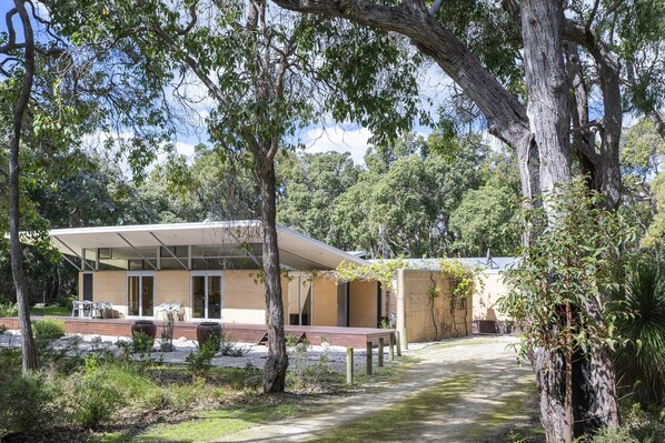 A modern building with a covered patio area, surrounded by trees and greenery.