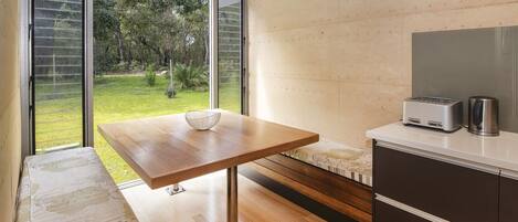 Una cocina moderna con una mesa de madera, horno empotrado y vistas a un jardín.