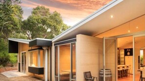 A modern house with large glass doors leading to a dining area.