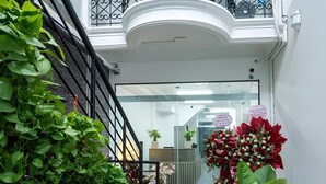 A staircase leading to a balcony with metal railings, surrounded by potted plants and a red flower arrangement. - Starlight Hotel Hanoi (Hanoi)