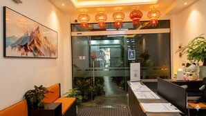 A hotel reception area with a large painting, a reception desk, a waiting area with seating, and a glass door leading to the interior. - Starlight Hotel Hanoi (Hanoi)