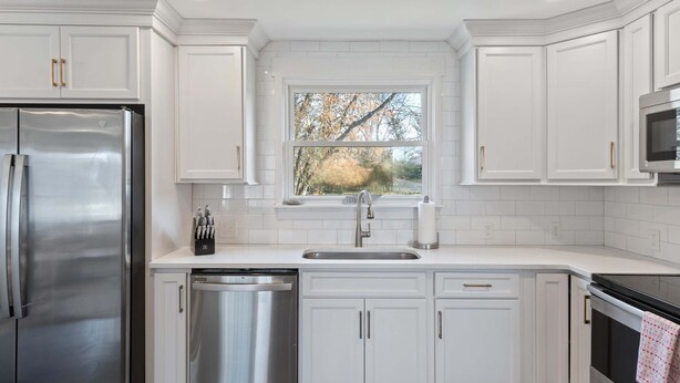 A modern kitchen with white cabinetry, stainless steel appliances, and a window providing a view of trees. - Family Retreat - 1 Mile to The Factory at Franklin (Franklin)